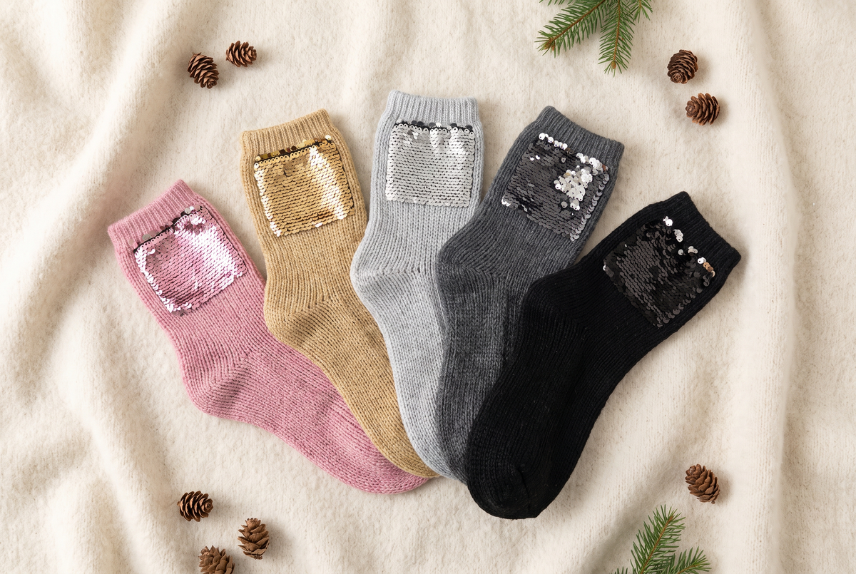 Plusieurs paires de chaussettes à paillettes de couleurs différentes disposées en éventail sur une couverture en laine
